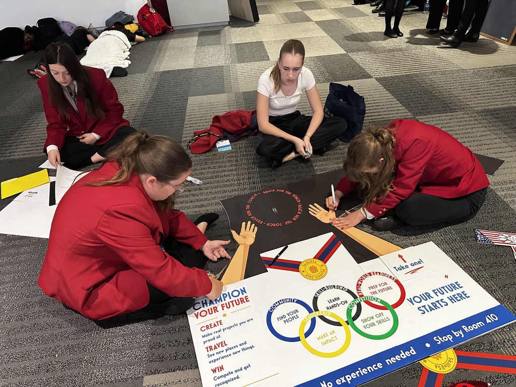 students seated on floor with sign