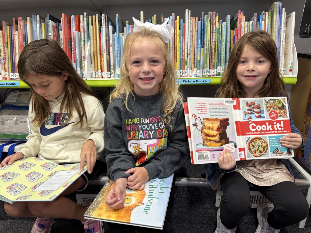 First Graders on the Bookmobile, one of which is wearing a shirt which reads, " Having fun isn't hard when you've got a Library Card"