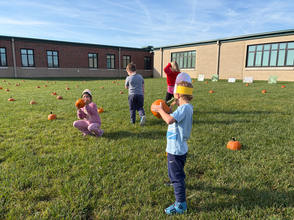 A group of four kindergarten students looking at pumpkins set out like a pumpkin patch outside of Bethel Elementary School