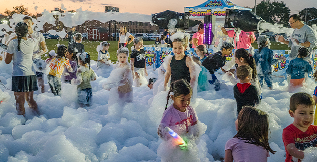Students playing with foam in front of school.