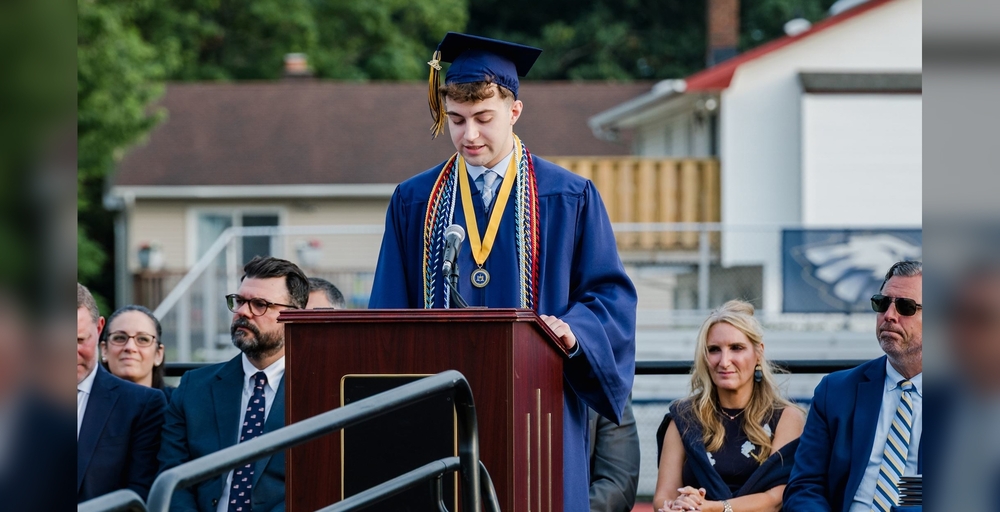 graduate in blue cap and gown at podium