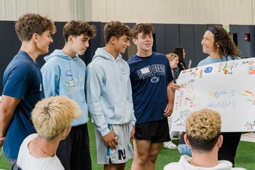 Student showing off poster board to other students.