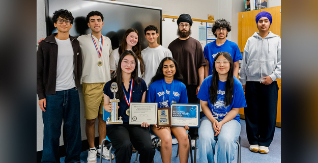A group of students celebrating academic achievements, holding trophies and certificates, together in a classroom setting.