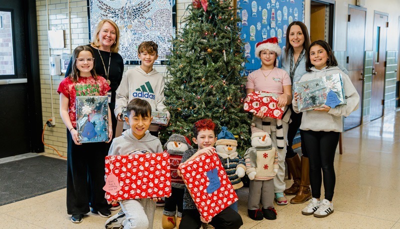people pose with gifts by tree