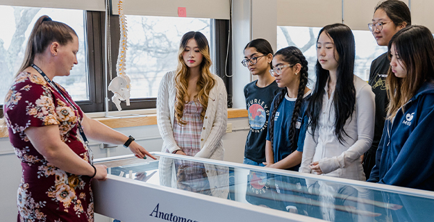 Teacher showing students something in a glass case.