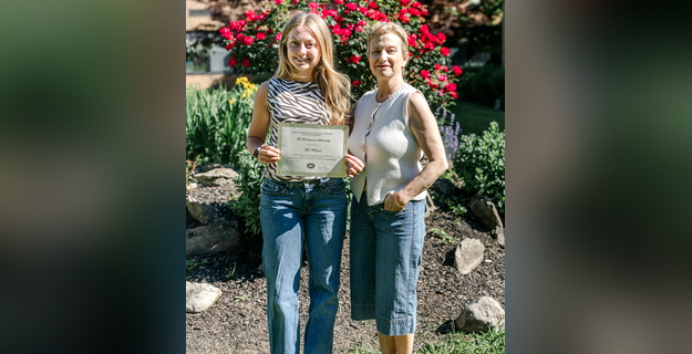two women one holding certificate in garden