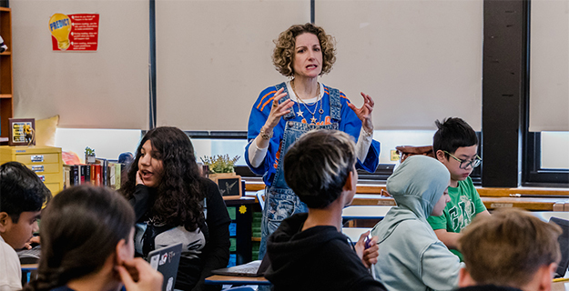 Teacher speakinig to students at their desks.