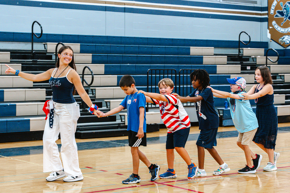 Student leading younger children in a line.