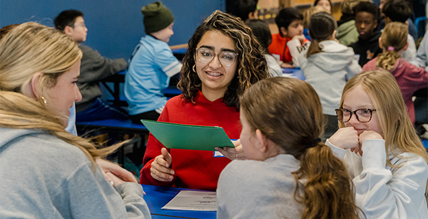 Student reading from pamphlet to others.