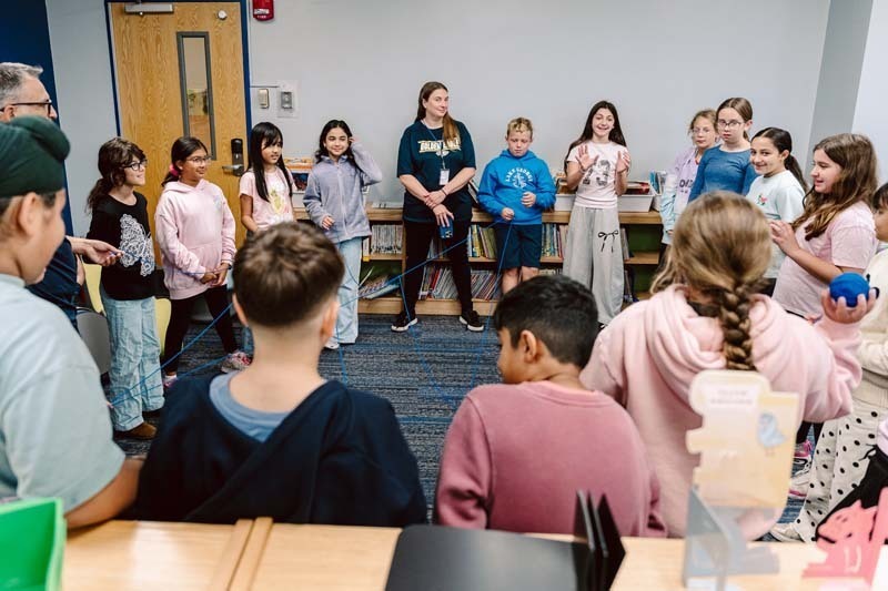 Students and teachers standing in circle in library.