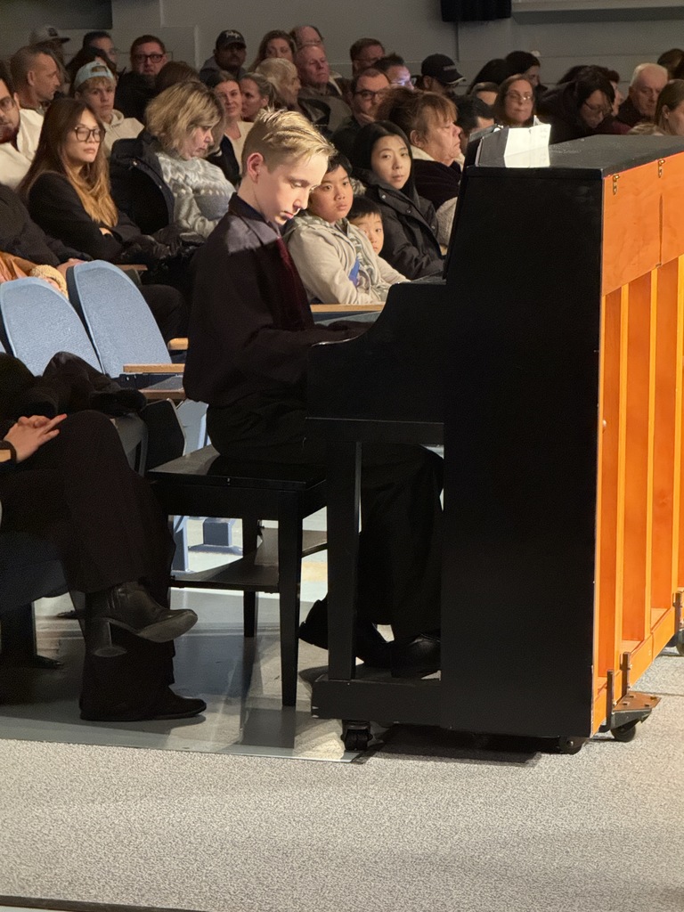 Christian Sachs playing a piano piece in between ensembles for the audience at the Winter Concert Part III