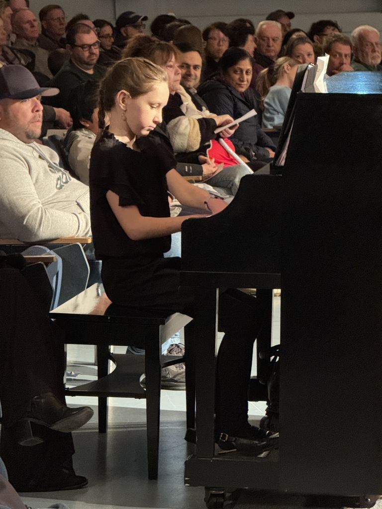 Josie Sachs playing a piano piece in between ensembles for the audience at the Winter Concert Part III