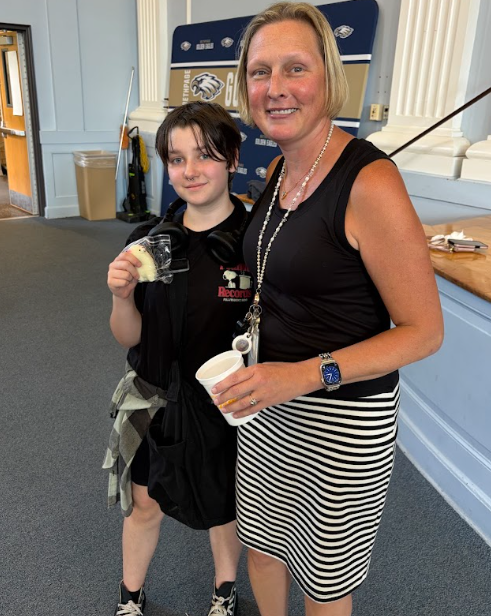 Principal Hayes and 7th grade assembly winner showing off their prize Llama squishy