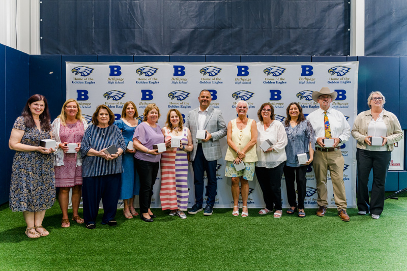 Group photo of award recipients at Bethpage High School event, celebrating achievements in front of a "Home of the Golden Eagles" backdrop.