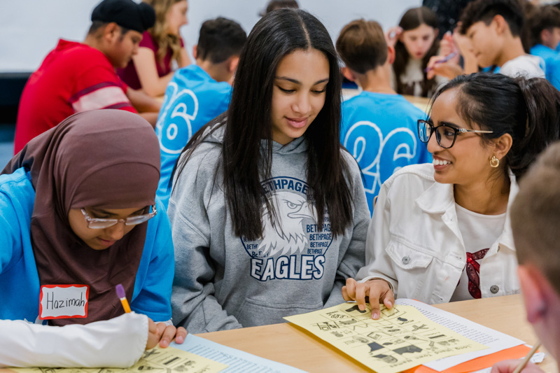 Students collaborating at a table, engaged in a creative learning activity, showcasing teamwork and academic engagement in a classroom setting.