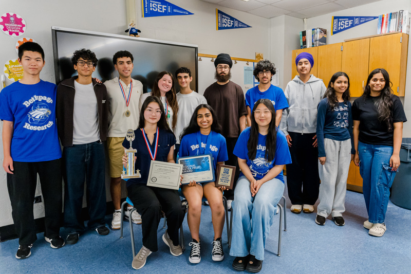 A group of students celebrating academic achievements, holding trophies and certificates, together in a classroom setting.