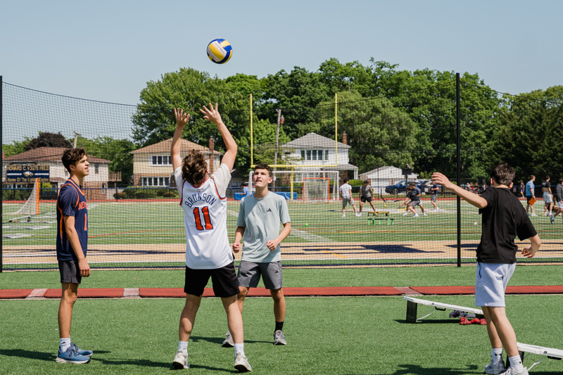 boys playing volleyball on field