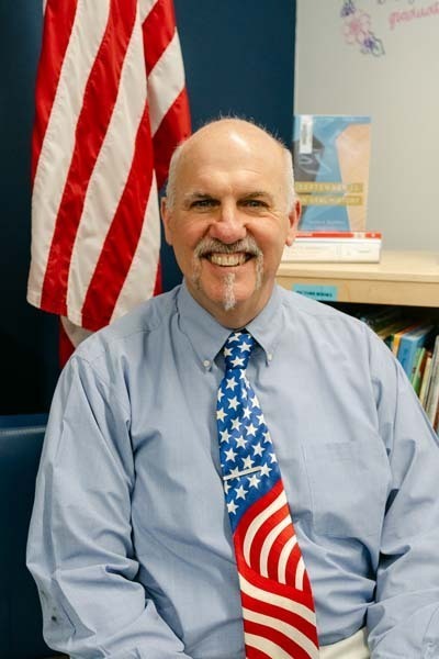Photo of teacher sitting at desk.