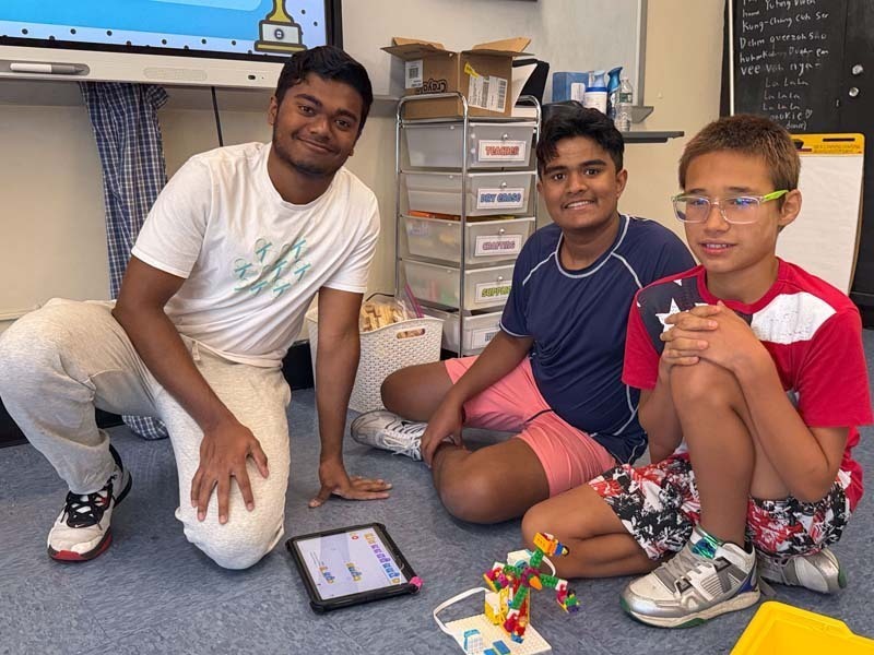 Students sitting on the floor, reading off of tablet.