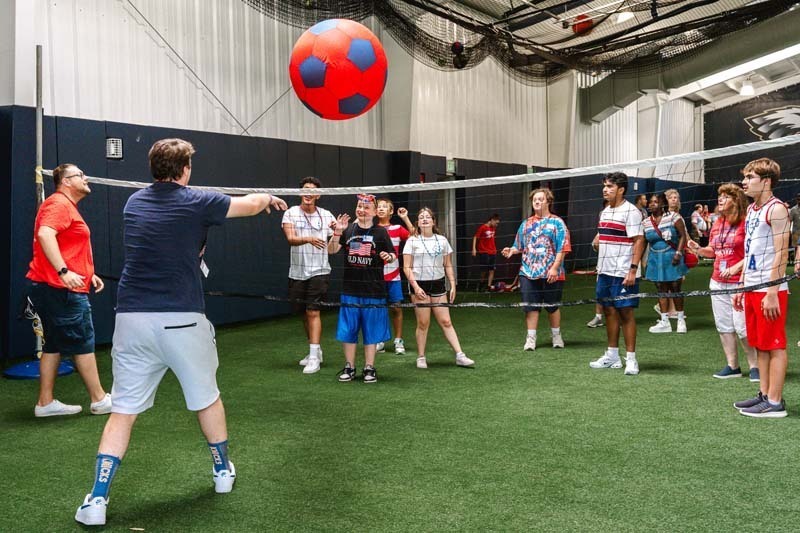 Students playing volleyball indoors.