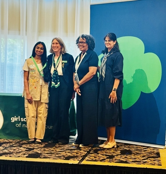 women by large decorative blue banner on stage