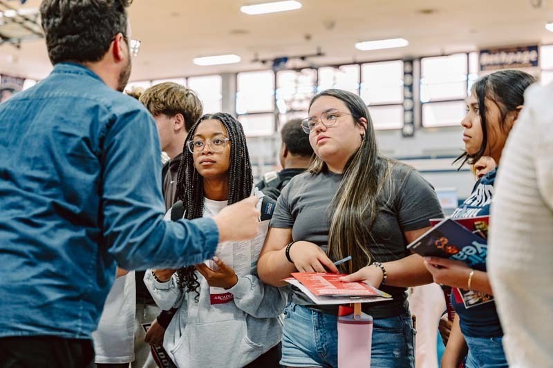 Students speaking to each other at college fair.