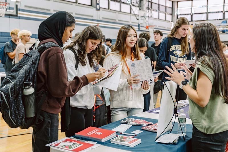 Students speaking to each other at college fair.