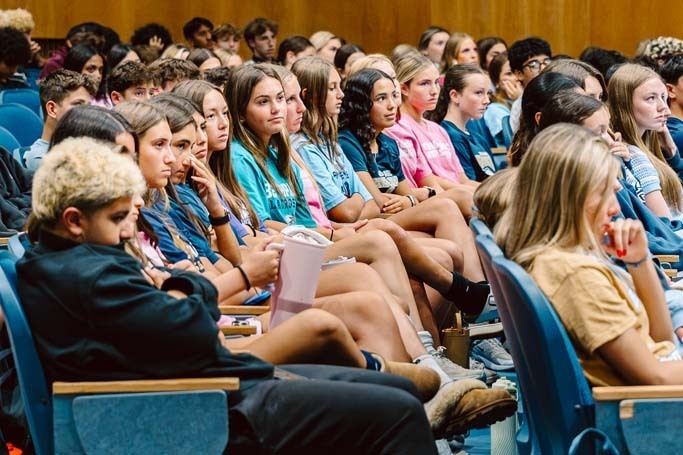 Students listening in auditorium.