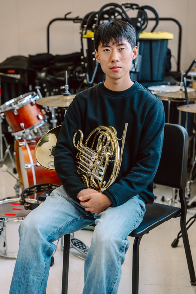 Person sitting with French horn in music room