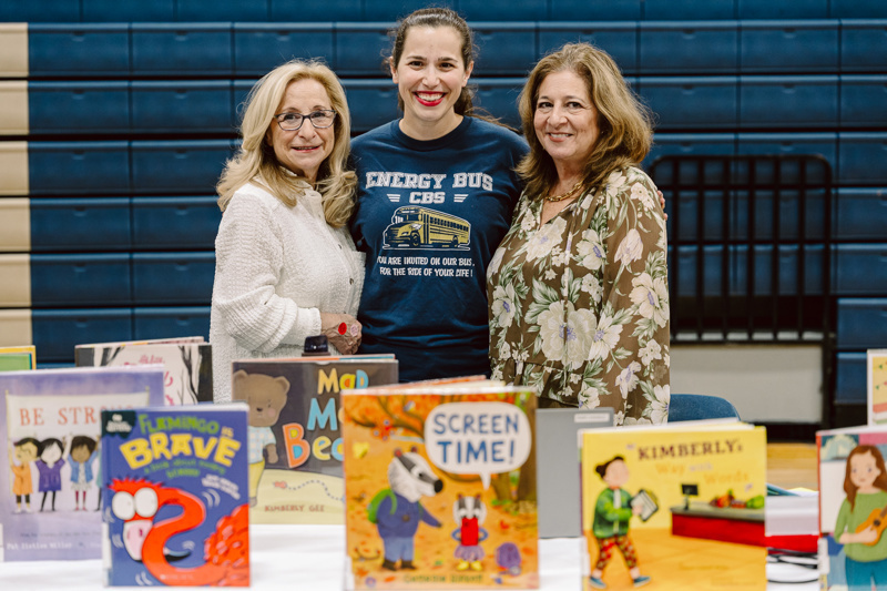 Group of three people at table of books