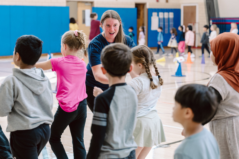 A group of people participate in an activity in a gym with colorful cones set
