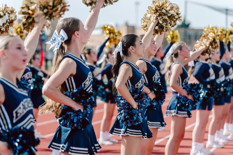 Cheerleaders in uniforms performing with pom poms