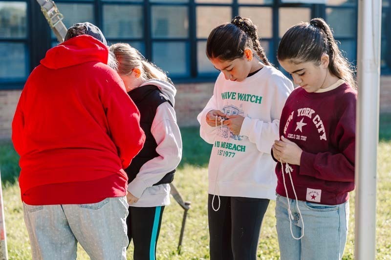 Students standing with teacher outside.