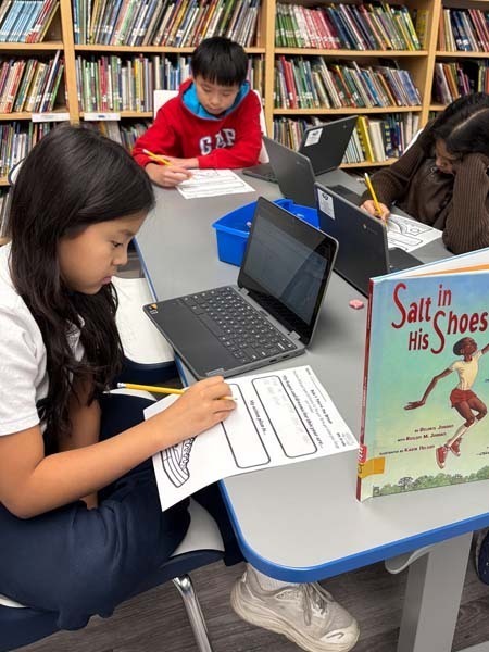 Student writing at desk.