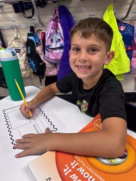 Student writing at desk.