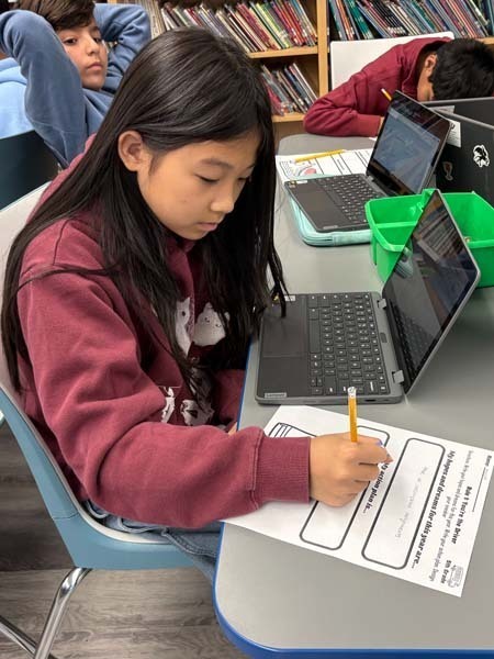 Student writing at desk.