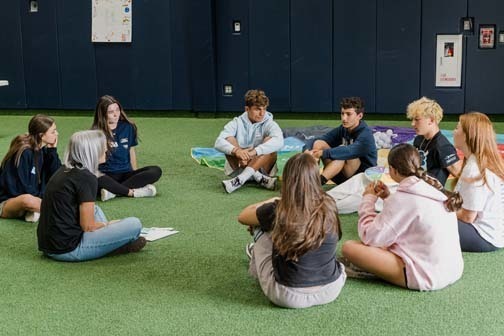 Students taling to each other in large group.