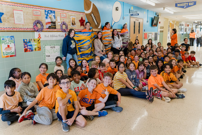 students sitting on floor in hall pose for a photo