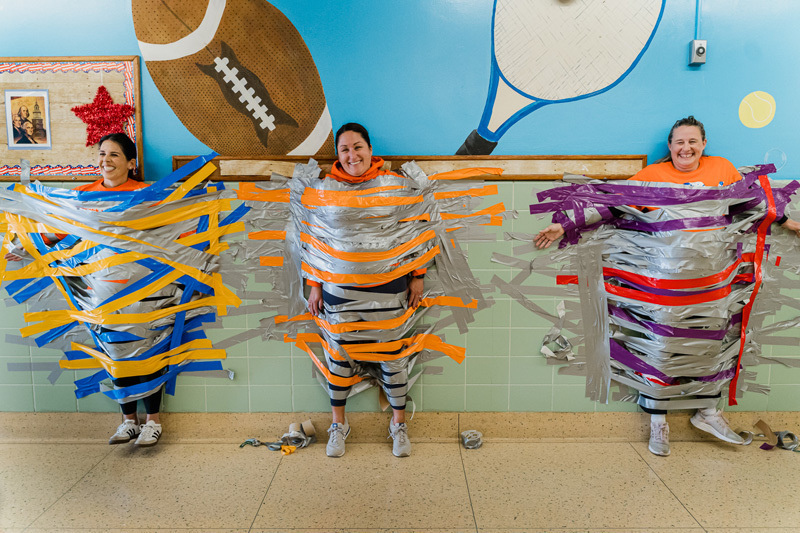 people spread out in hallway taped to the wall with colored tape