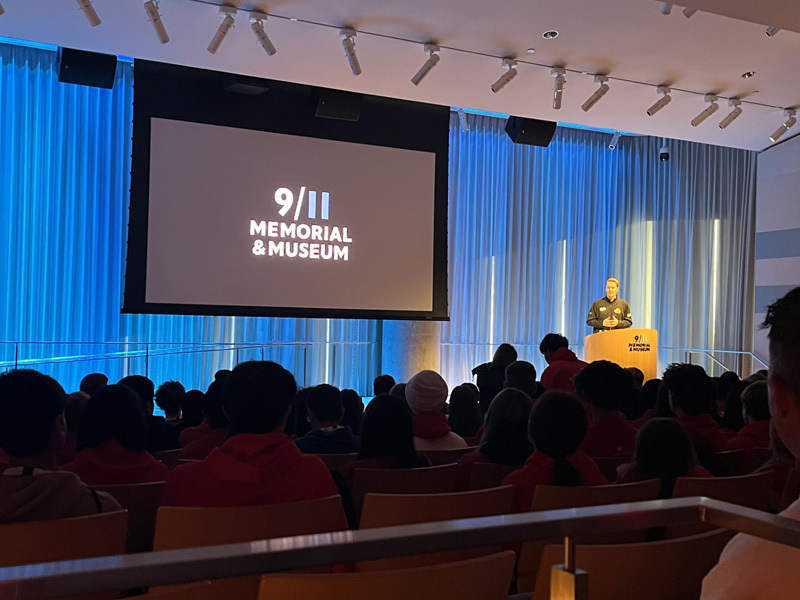 students watching the movie screen in the auditorium of the museum