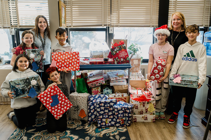 people pose with gifts by tree