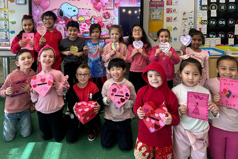 A group of young children and a teacher pose in a decorated school hallway.