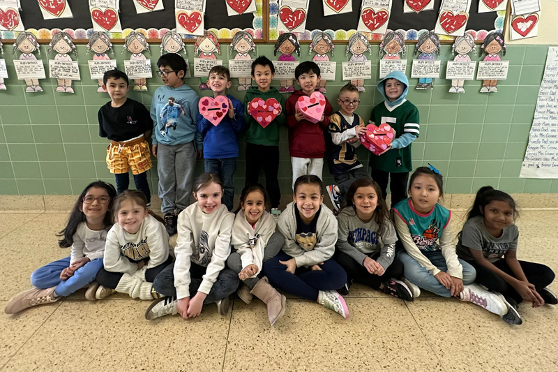 A group of young children and a teacher pose in a decorated school hallway.