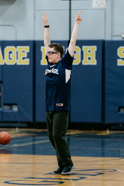 players wearing a “Golden Eagles” jerseyplaying basketball on a gym court, focused and determined. Blurred spectators watch in the background.