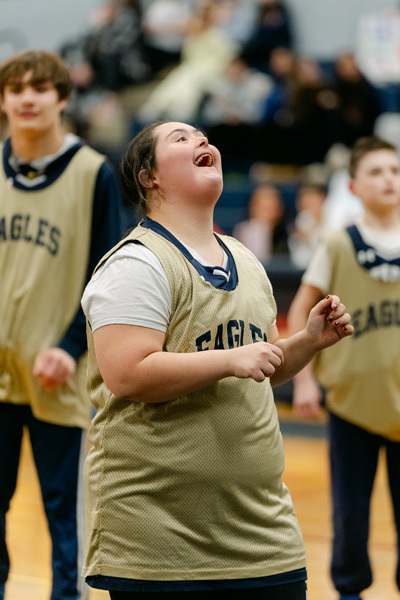 players wearing a “Golden Eagles” jerseyplaying basketball on a gym court, focused and determined. Blurred spectators watch in the background.