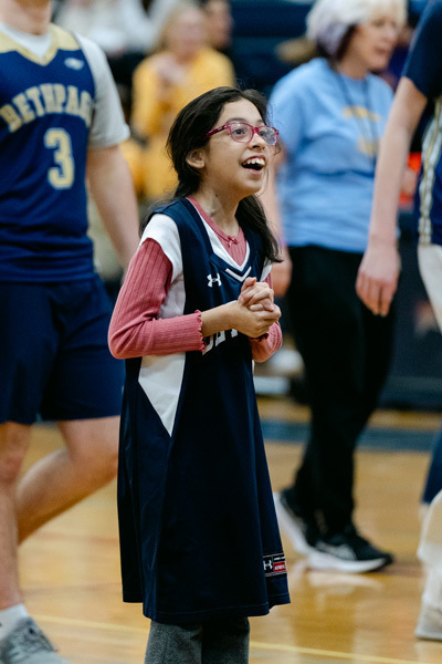 players wearing a “Golden Eagles” jerseyplaying basketball on a gym court, focused and determined. Blurred spectators watch in the background.