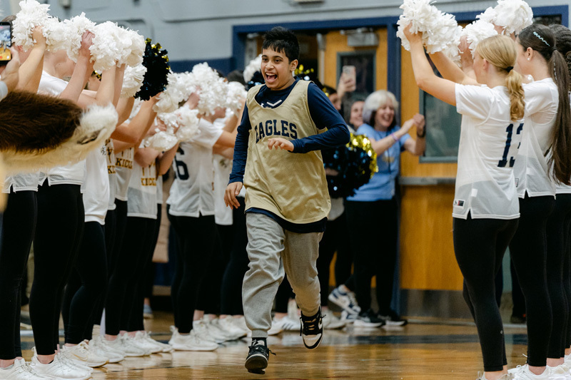 players wearing a “Golden Eagles” jerseyplaying basketball on a gym court, focused and determined. Blurred spectators watch in the background.