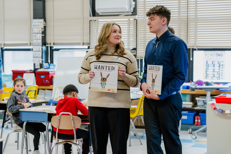 people read books to seated children in a classroom.