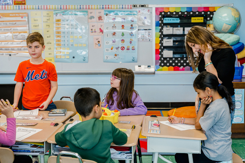people read books to seated children in a classroom.