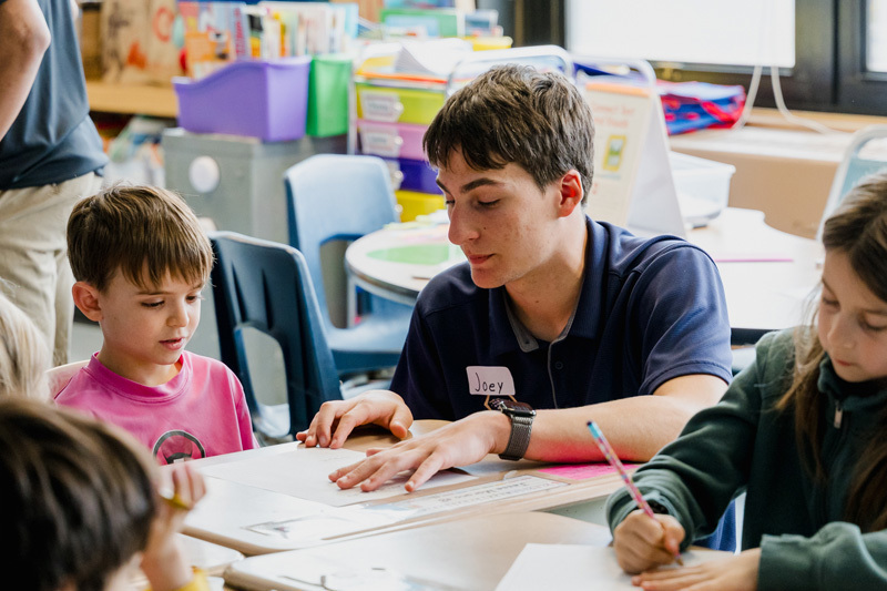 people read books to seated children in a classroom.